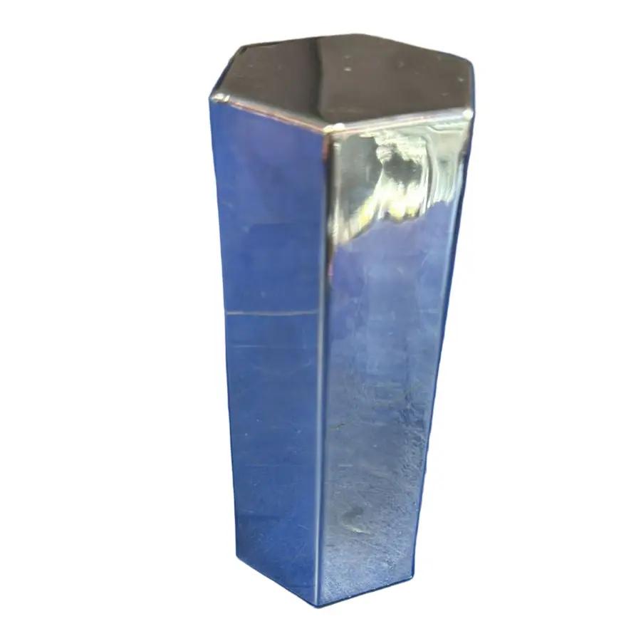 A high thread hexagonal nut cover lying on a blue surface.